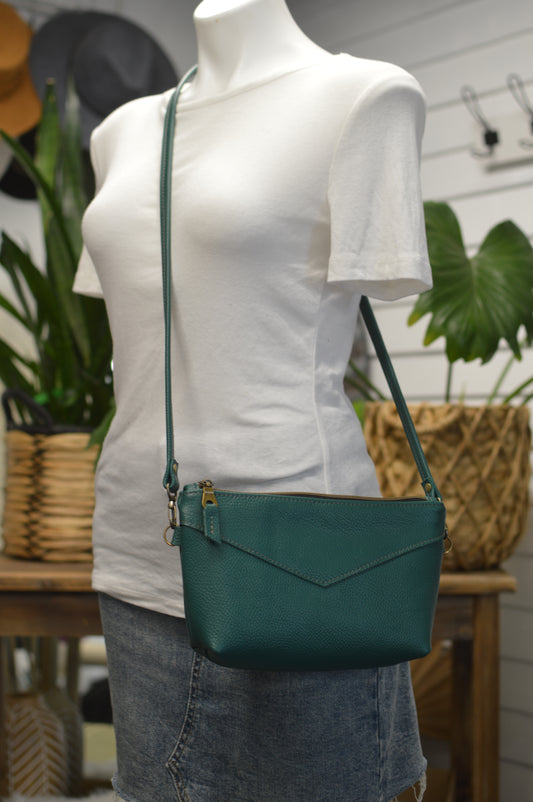 Handcrafted leather bags made one at a time in Maine

Ruby Crossbody bag:

Made with Pavone green teal Italian leather with antique bronze hardware!

Measures 7”x11” with 1.5” boxes corners Crossbody 
47” long thin leather strap
Lining includes a zippered pocket and 3 card slots!
Lined with cream waterproof canvas.